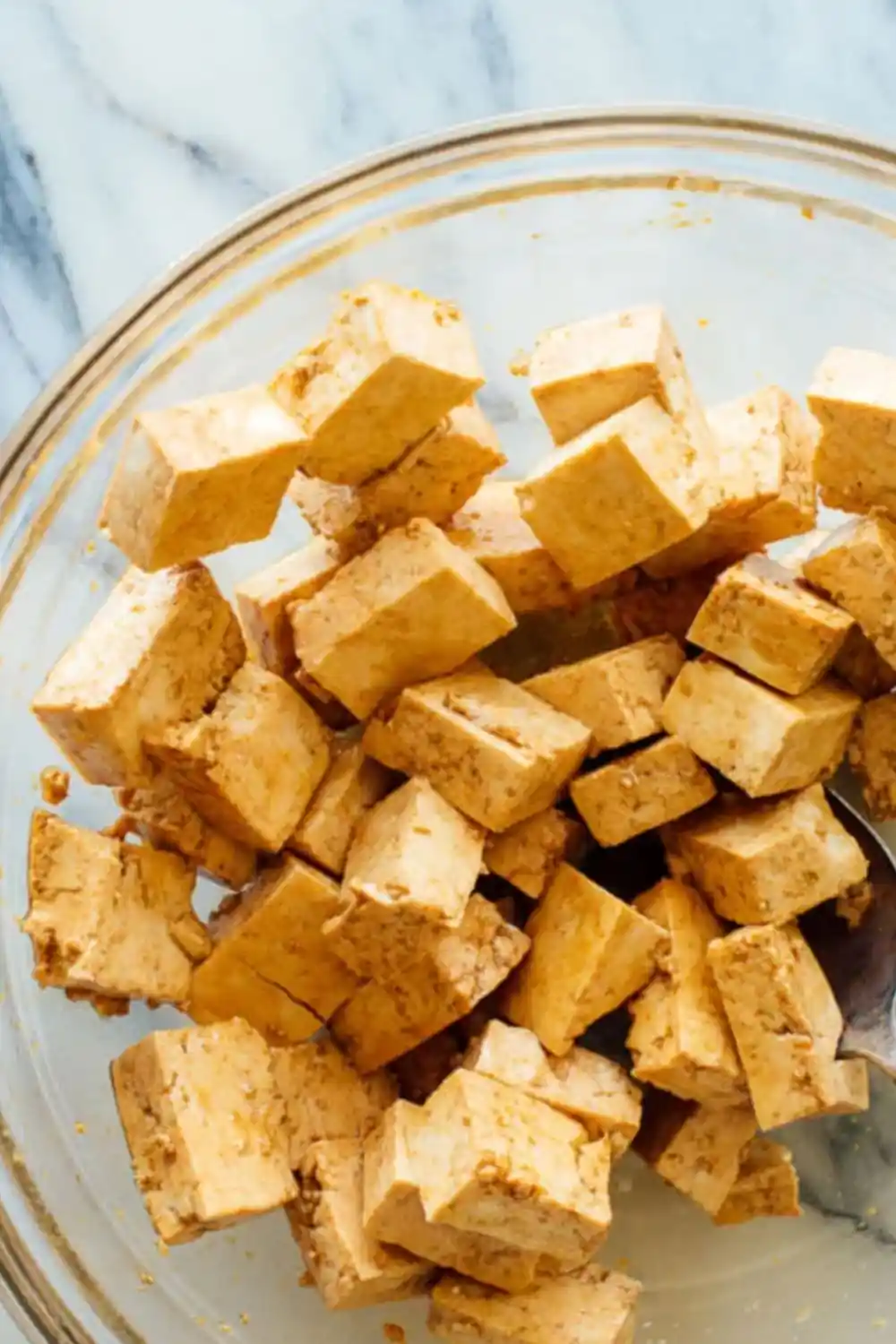 Crispy tofu bites marinated in soy sauce in a glass bowl