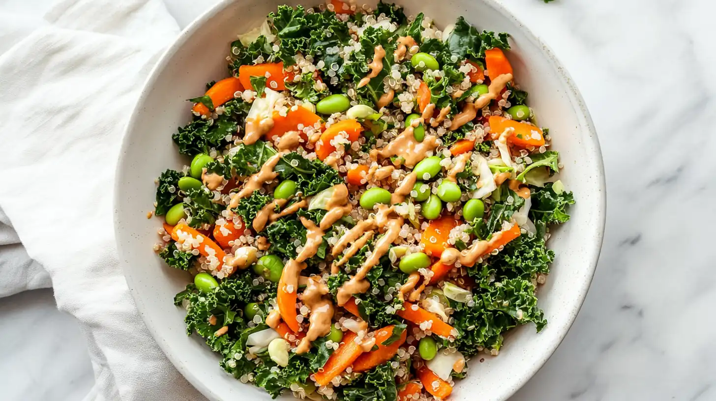 overhead view of edamame quinoa salad with kale, carrots, and creamy tahini in a white bowl