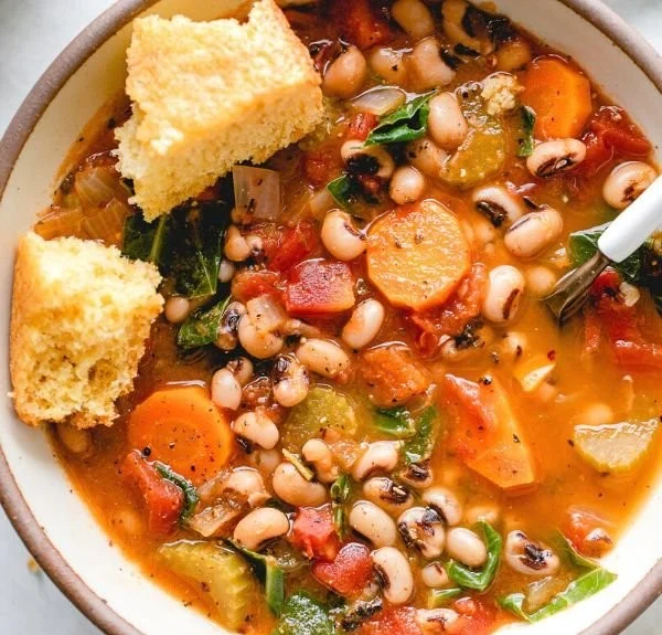 Bowl of smoky black eyed pea soup garnished with herbs and spices