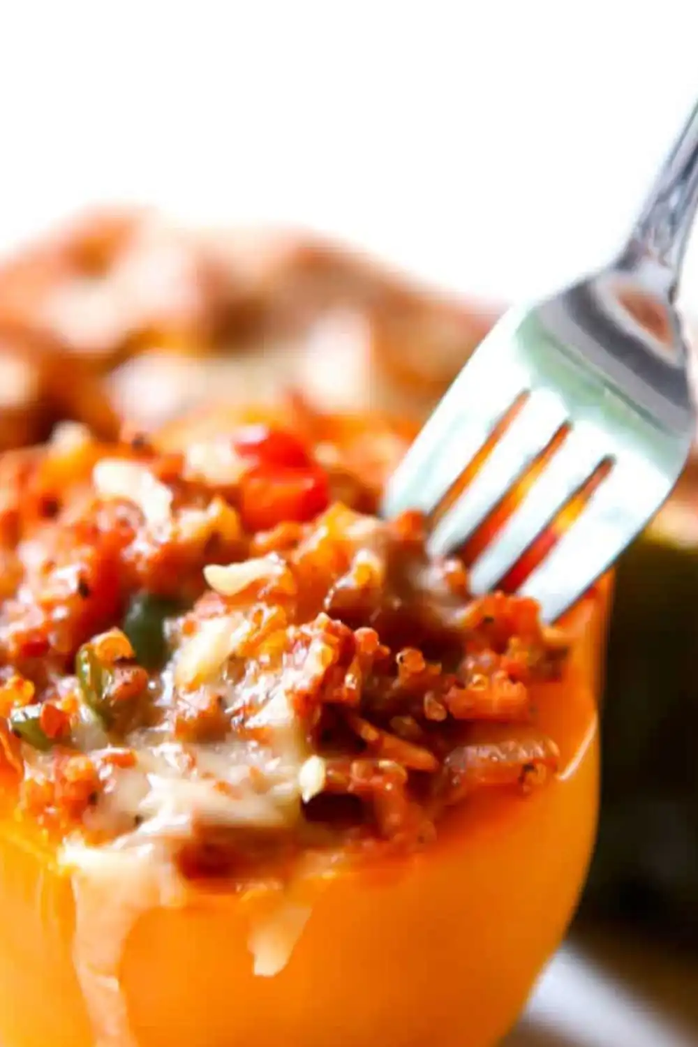 Close-up of fork scooping cheesy filling from vegan Italian stuffed yellow bell pepper