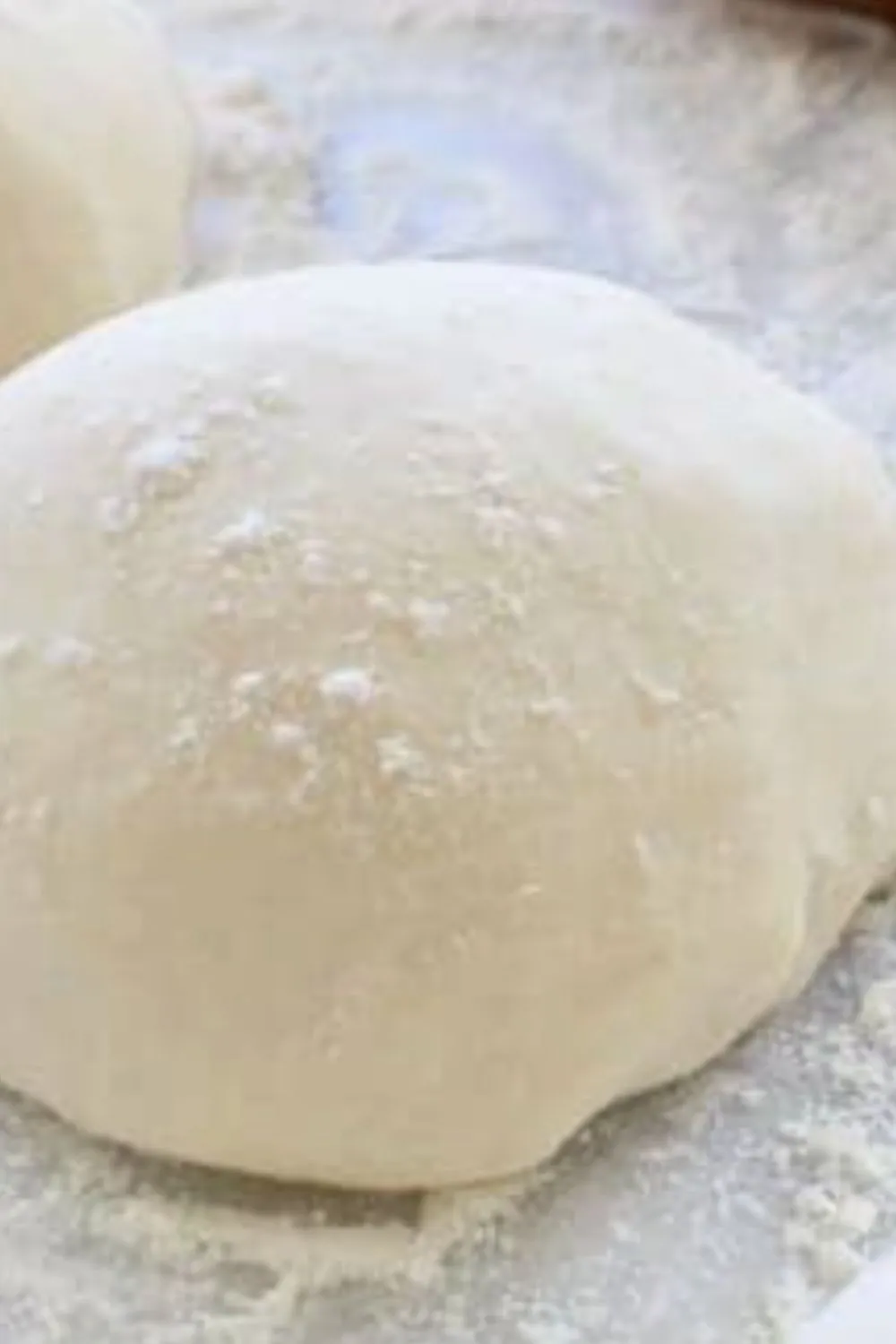 smooth vegan pizza dough ball resting on floured surface