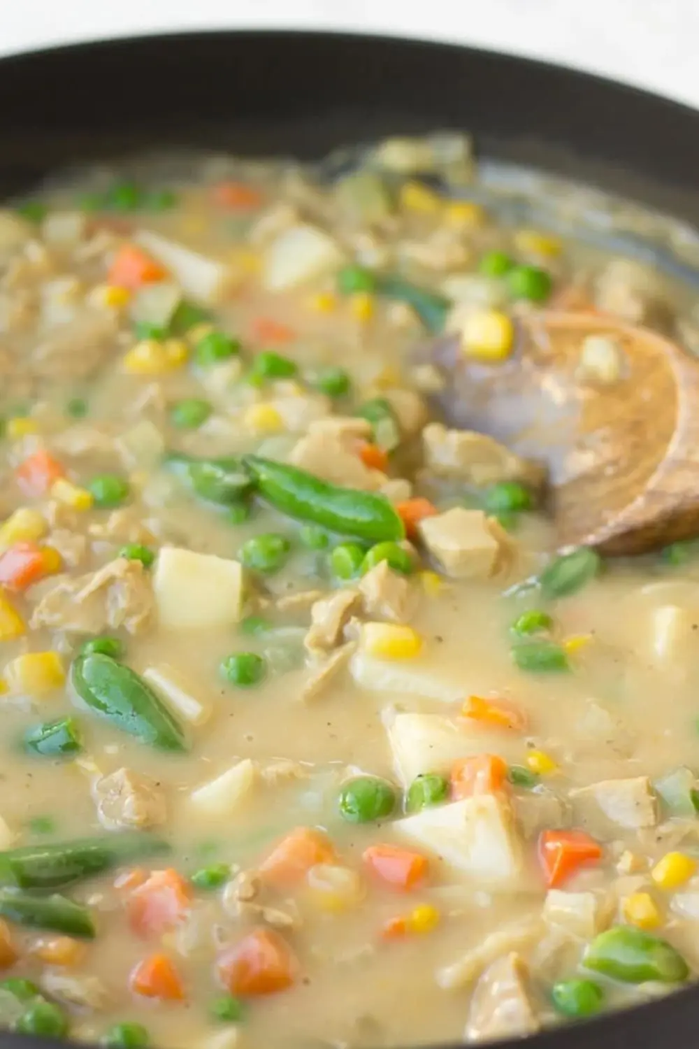creamy vegan pot pie filling with peas, carrots, potatoes and green beans in a skillet