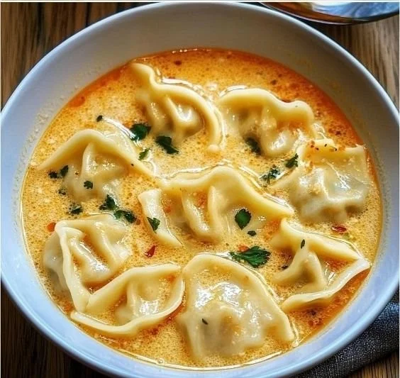 Bowl of creamy Thai dumpling soup garnished with herbs and spices