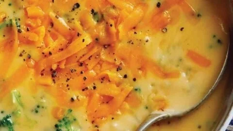 Bowl of easy homemade broccoli cheddar soup garnished with cheese and herbs