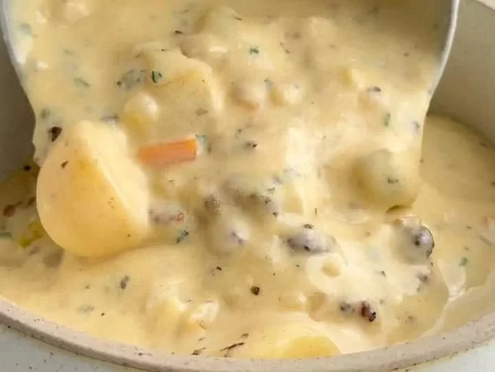 Bowl of legendary sausage potato soup garnished with herbs and served hot.