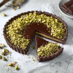 Delicious dark chocolate pistachio tart on a white plate