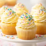 Delicious homemade vanilla cupcakes with frosting on a decorative plate.