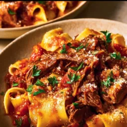 Instant Pot Lamb Ragu 3 A delicious bowl of Instant Pot lamb ragu served with pasta and garnished with herbs.