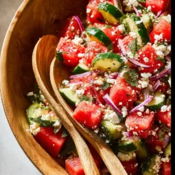 A colorful bowl of watermelon cucumber salad with mint leaves and lime dressing.
